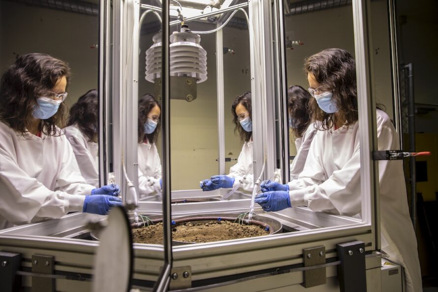 A masked scientist handling a sample in the EcoPod